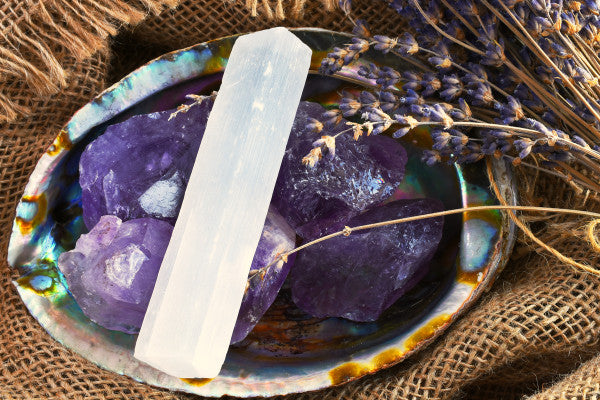 cleansing crystals how to what to use selenite bar sitting on raw amethyst in an abalone shell on burlap close up