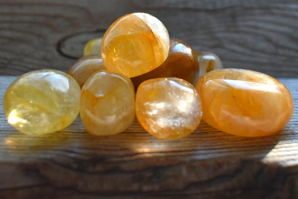 golden quartz healing properties benefits uses close up of pile of tumbled golden healers quartz on wood