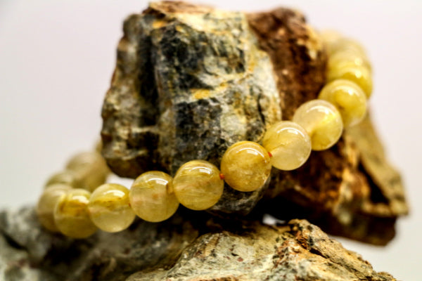 golden quartz healing properties benefits uses golden healers quartz bracelet resting on raw quartz stone