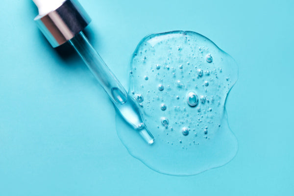 how hyaluronic acid works close up of dropper spilling HA on baby blue surface