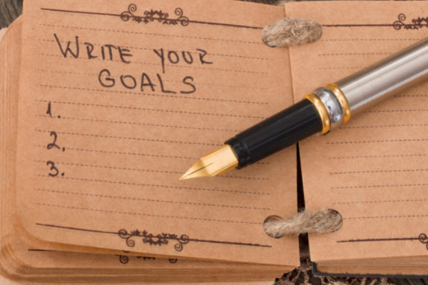 setting new year's resolutions that'll stick set specific goals close up of notebook with list and a pen