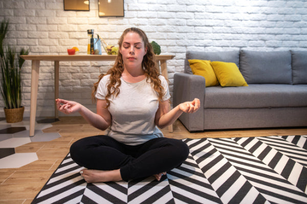 the best breathing techniques for stress relief person sitting in living room practicing breathing meditating