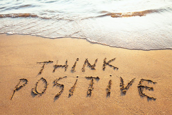 the power of positive thinking think positive written in the sand on the beach waves rolling up