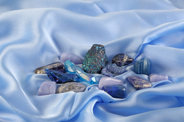 throat chakra stones affirmations essential oils and more healing crystals on blue silk close up