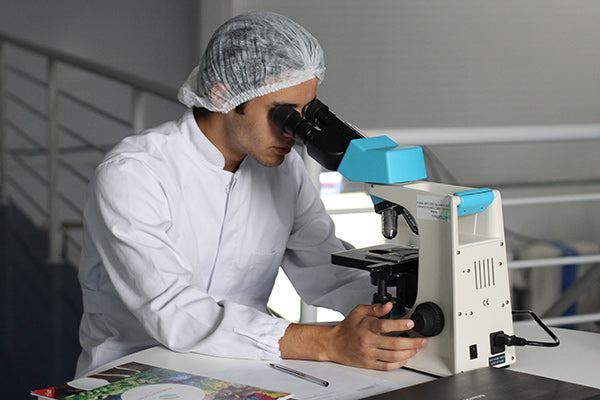 using dmso for muscle pain relief scientist looking through a microscope studying DMSO white lab coat blurred background