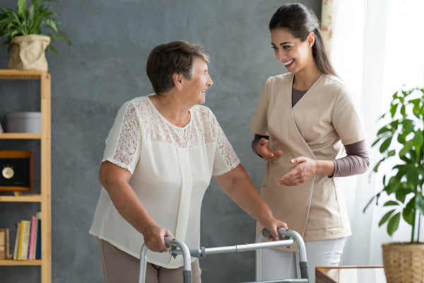 what is parkinsons disease nurse helping a woman using a walking both smiling