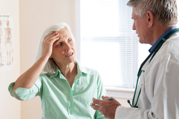 what is temporal arteritis symptoms of temporal arteritis treatment for temporal arteritis elderly woman holding her head in pain talking to her doctor at an office visit