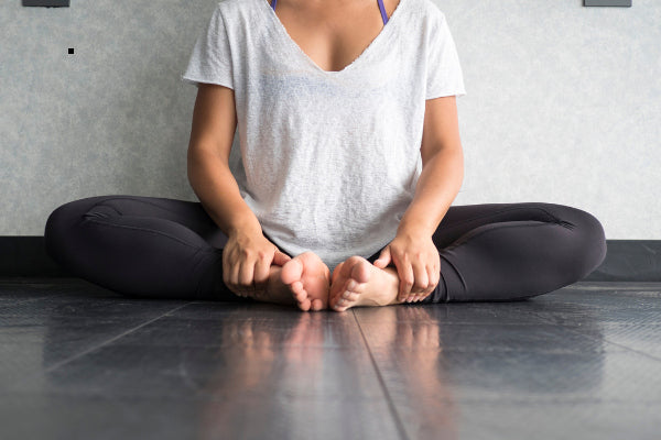 yoga for chronic pain relief woman sitting against the wall doing butterfly pose close up