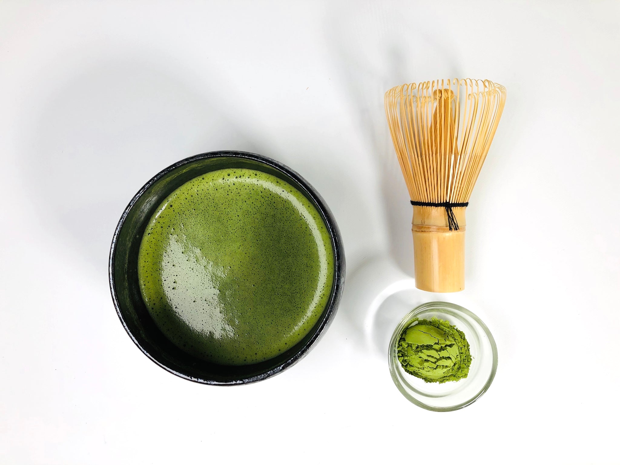 prepared matcha in bowl with matcha whisk and powdered matcha