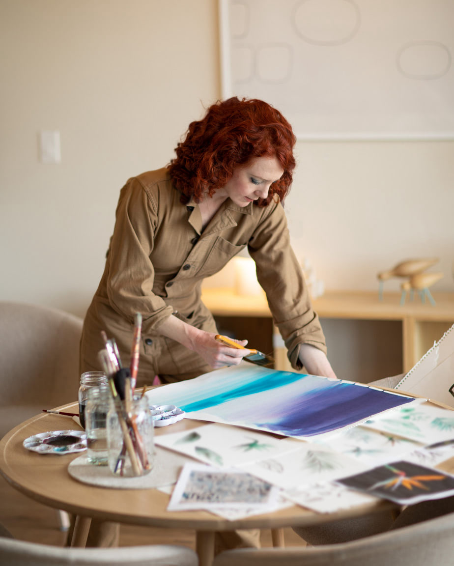 Heidi Lister Hevesy de pé numa mesa e a pintar com aguarelas