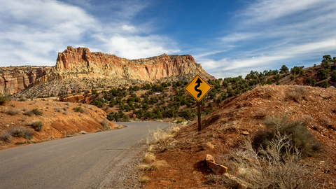 A dirt road and curves ahead sign set in the Utah canyon desert Grand Staircase 