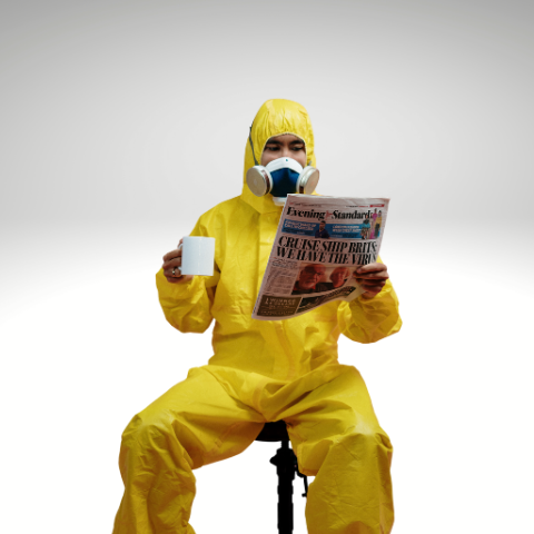 Man sitting in hazmat suit drinking coffee and reading paper