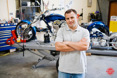 Man in auto shop with motorcycle in the background