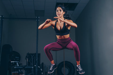 woman jumping while working out in purple leggings