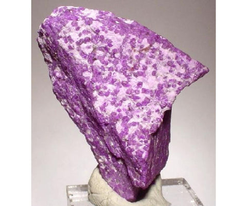 A close-up image of a purple mineral specimen, resembling sugilite stone