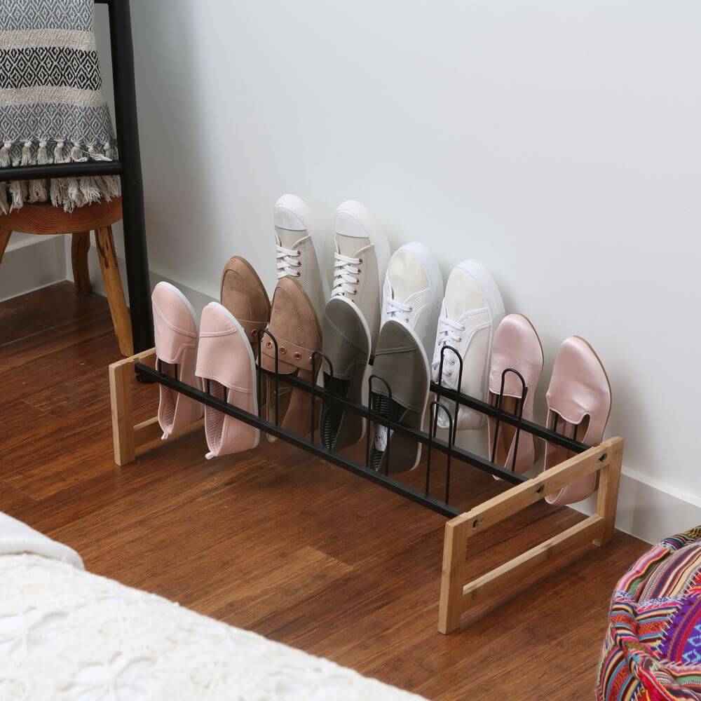 A black and bamboo freestanding shoe rack. On the rack are six pairs of shoes.