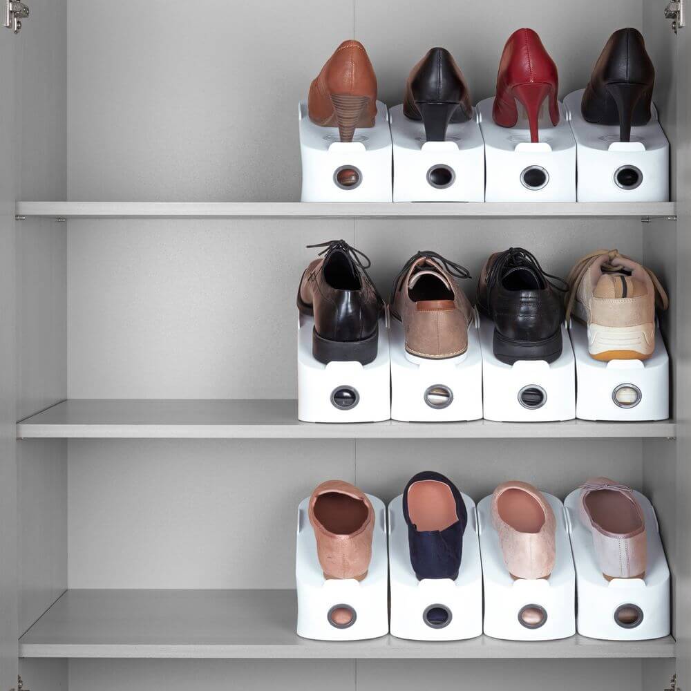 White shoe stackers on a wardrobe shelf. Each stacker top-and-tails a pair of high heels, dress shoes and casual shoes to save space.