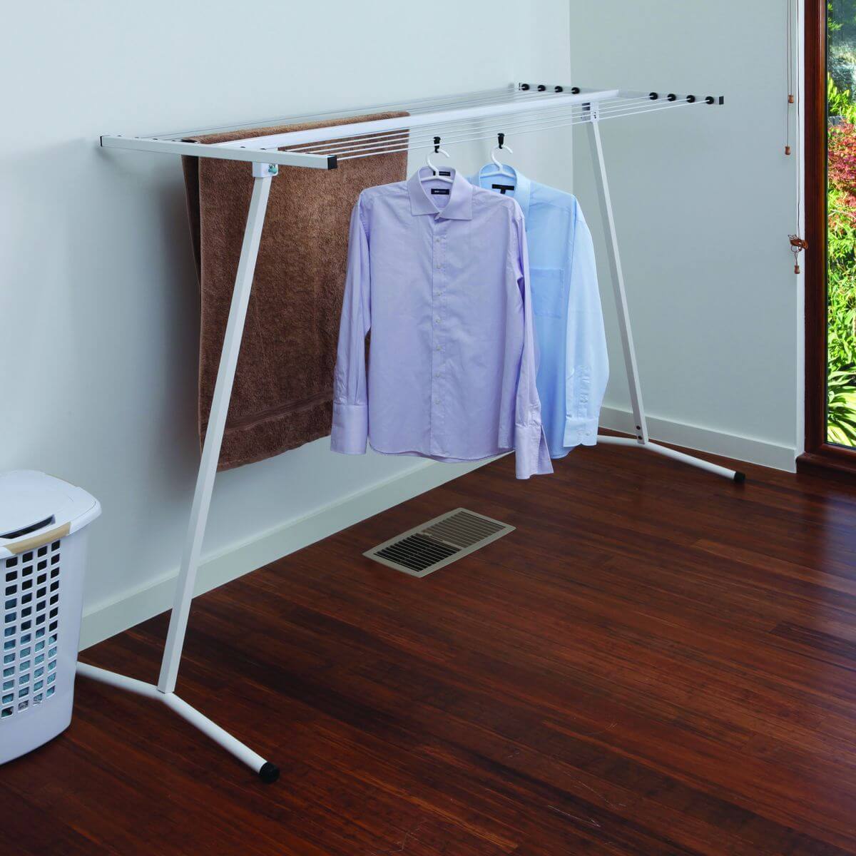 A large white freestanding clothesline used indoors to hang laundry