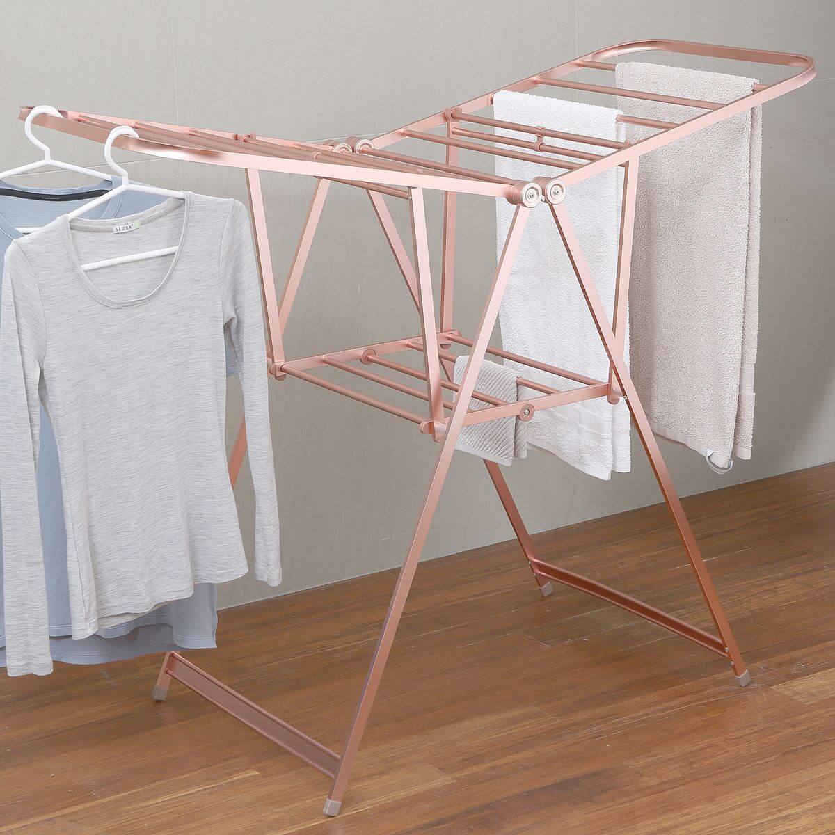A rustproof aluminium clothes airer in rose gold being used for drying laundry