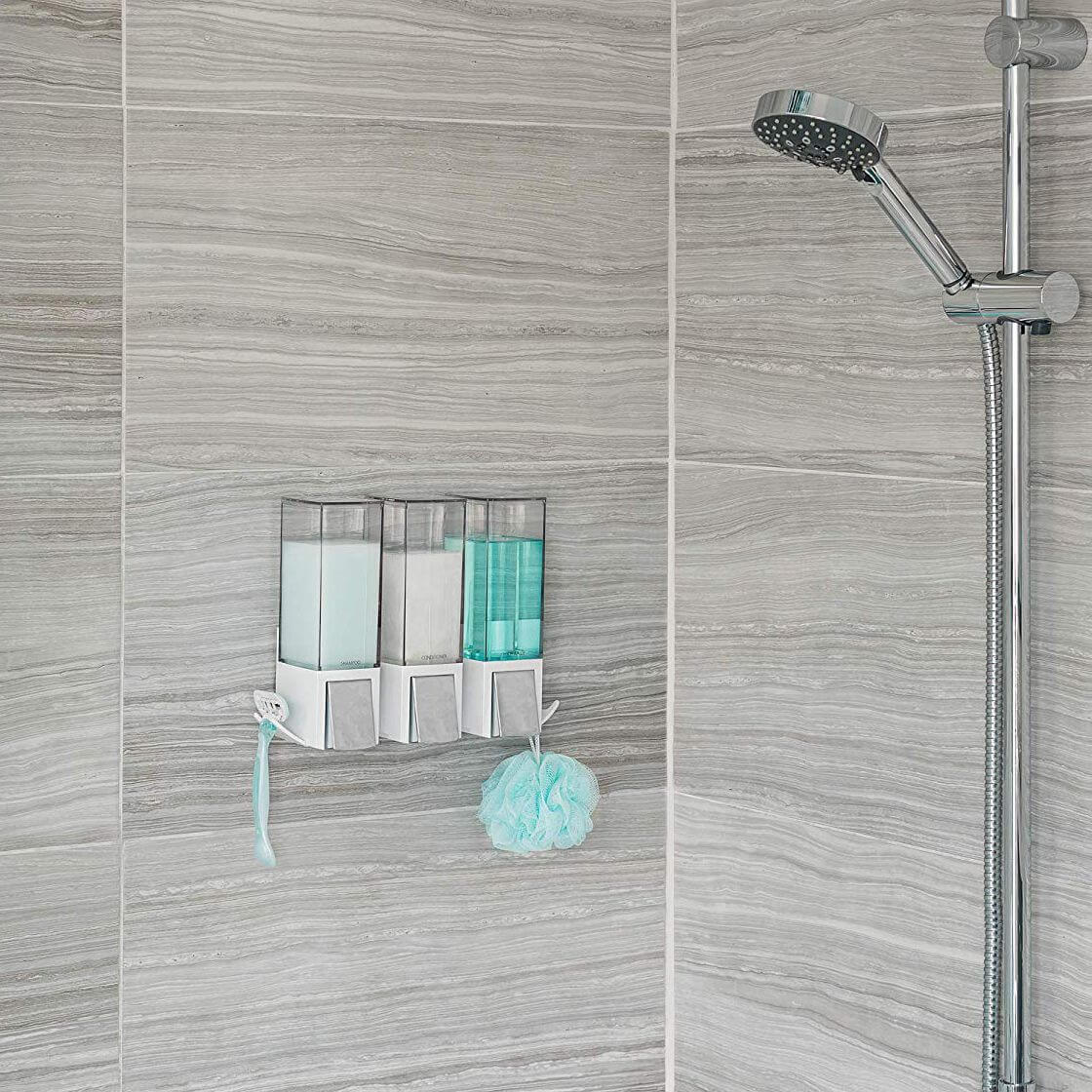 A white shower soap dispenser attached to a tiled shower wall with silicone glue