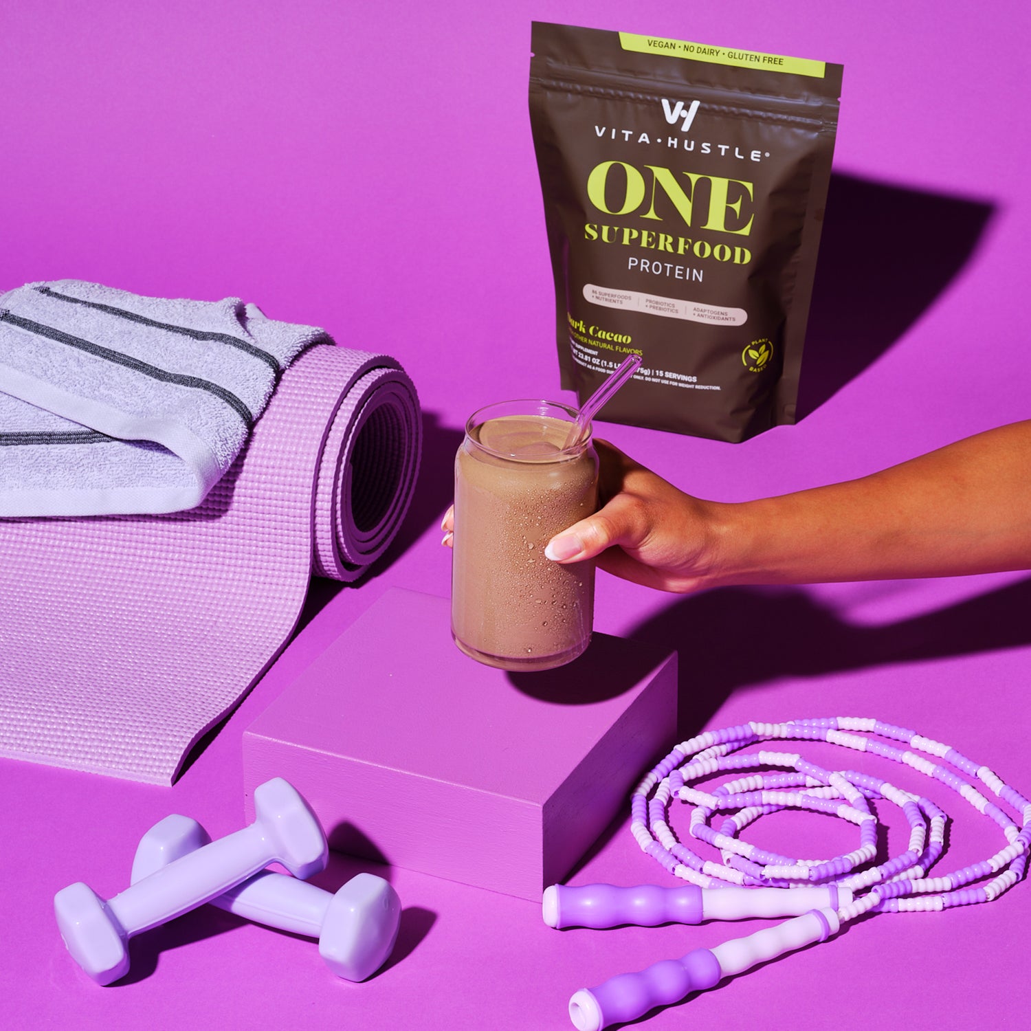 Fitness equipment and a VitaHustle protein shake on a purple background.