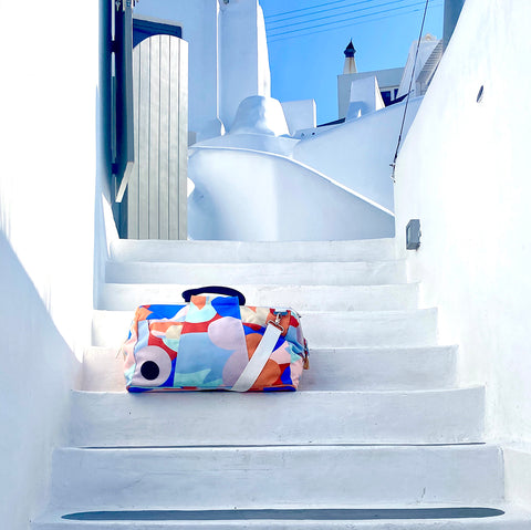Vibrant multicoloured travel bag on the steps in Santorini