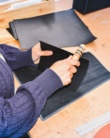 Simone smoothing leather edges in a workshop