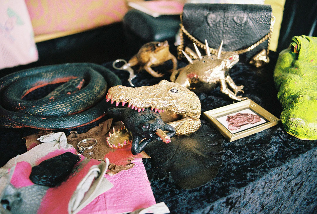 ornaments found inside Lia Tabrah's creative studio. a gold crocodile head figure has captured a black cane toad smoking a cigarette.