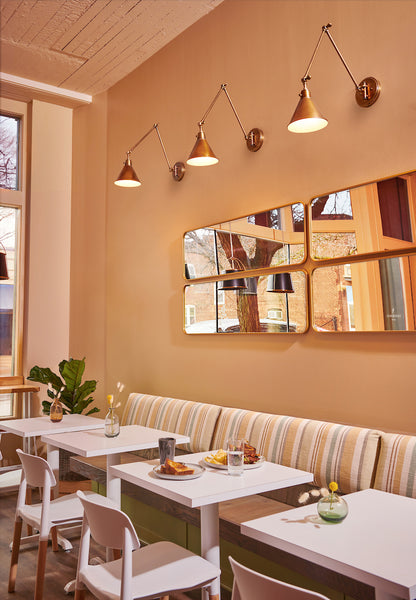 Swing-Arm Wall Lamp showcased as focused lighting in a small cafe setting.