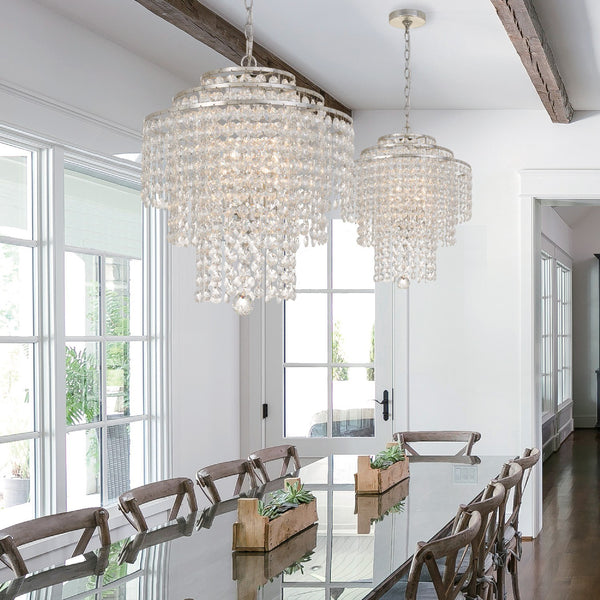 Two crystal chandeliers showcased in a large modern dining room.