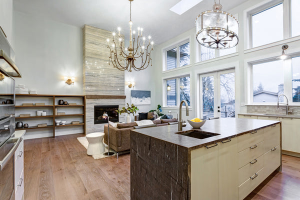 A large chandelier showcased as fixture focal point of a living room and a drum shade chandelier above a kitchen island.