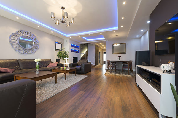 Chandelier along with recessed and cove lighting providing ambient lighting in a modern living room.