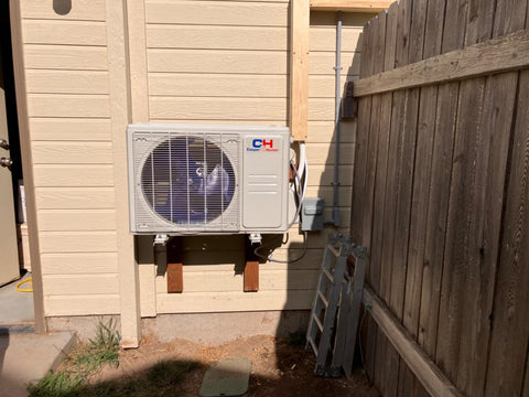 Wall Unit Sitting on a platform next to a fence inside of a homeowners yard