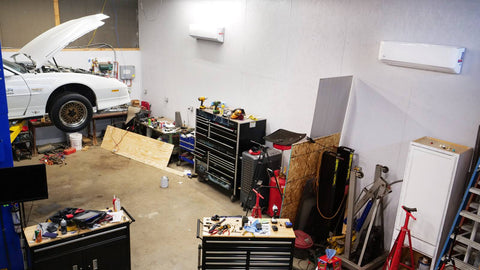 Two Indoor units inside of a sizeable mechanics garage with an open white car being currently worked on