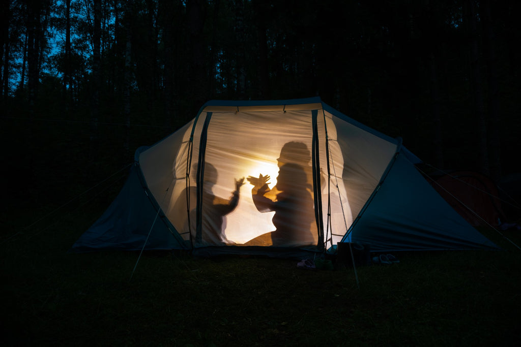 family in a tent playing with flashlight shadows