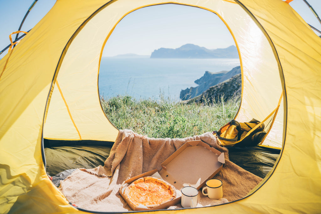 Une pizza à emporter dans une boîte brune à la tente de camping de la côte..