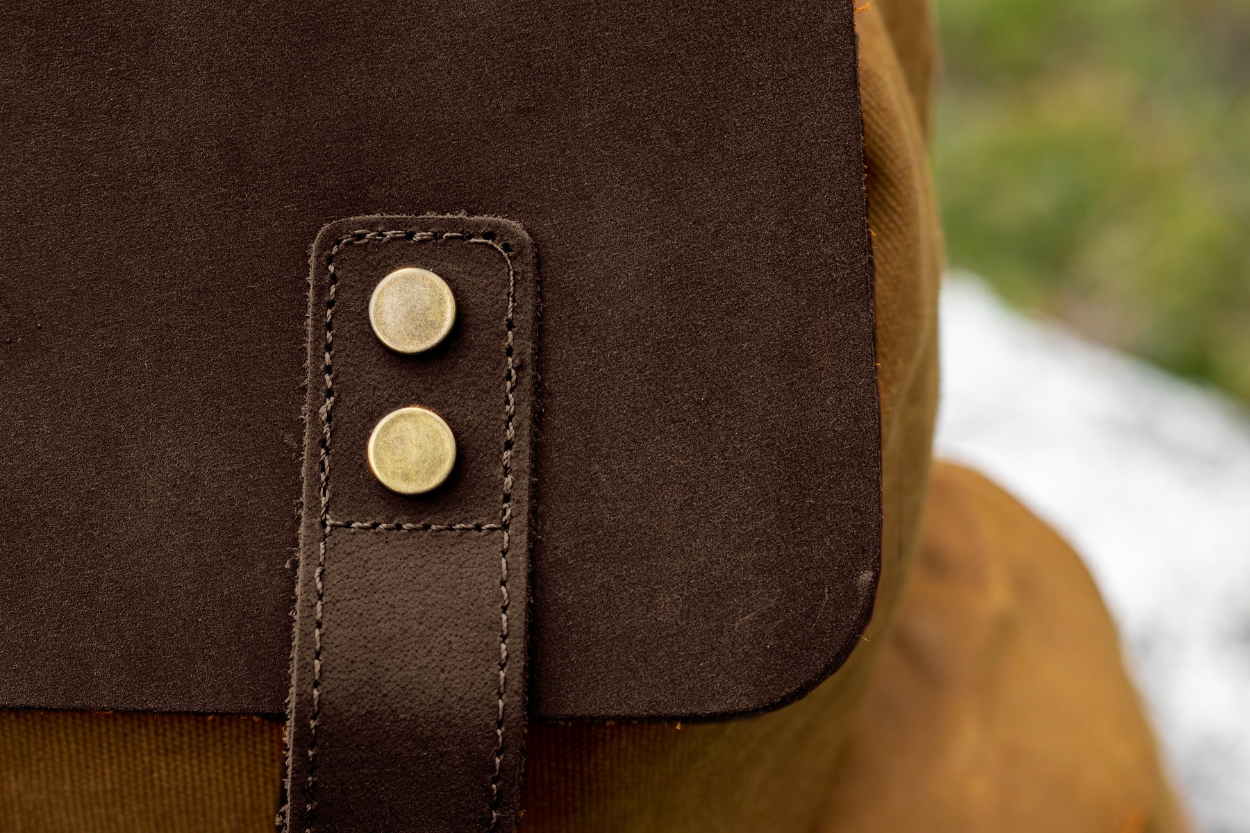 close up view of the gold tone protective rivet on the brown leather cap with a drawstring closure of the waxed full grain leather and canvas vintage backpack