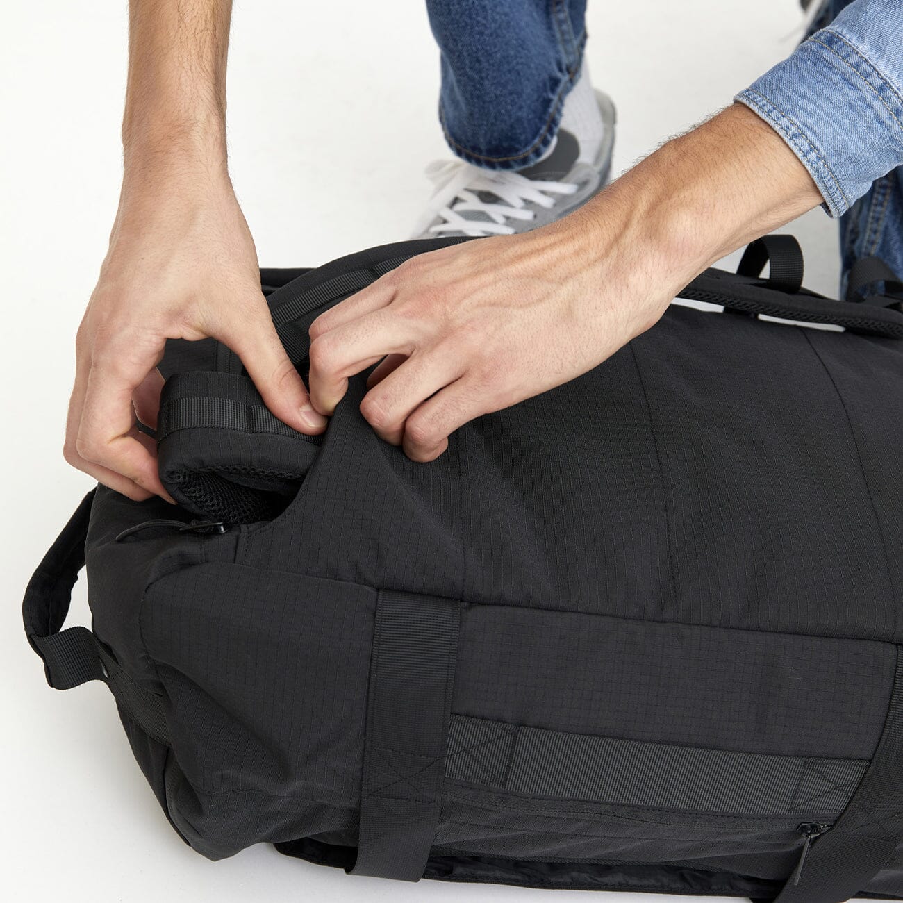 Close-up of adjustable, detachable shoulder straps sliding into their storage pocket on the Wanderer backpack