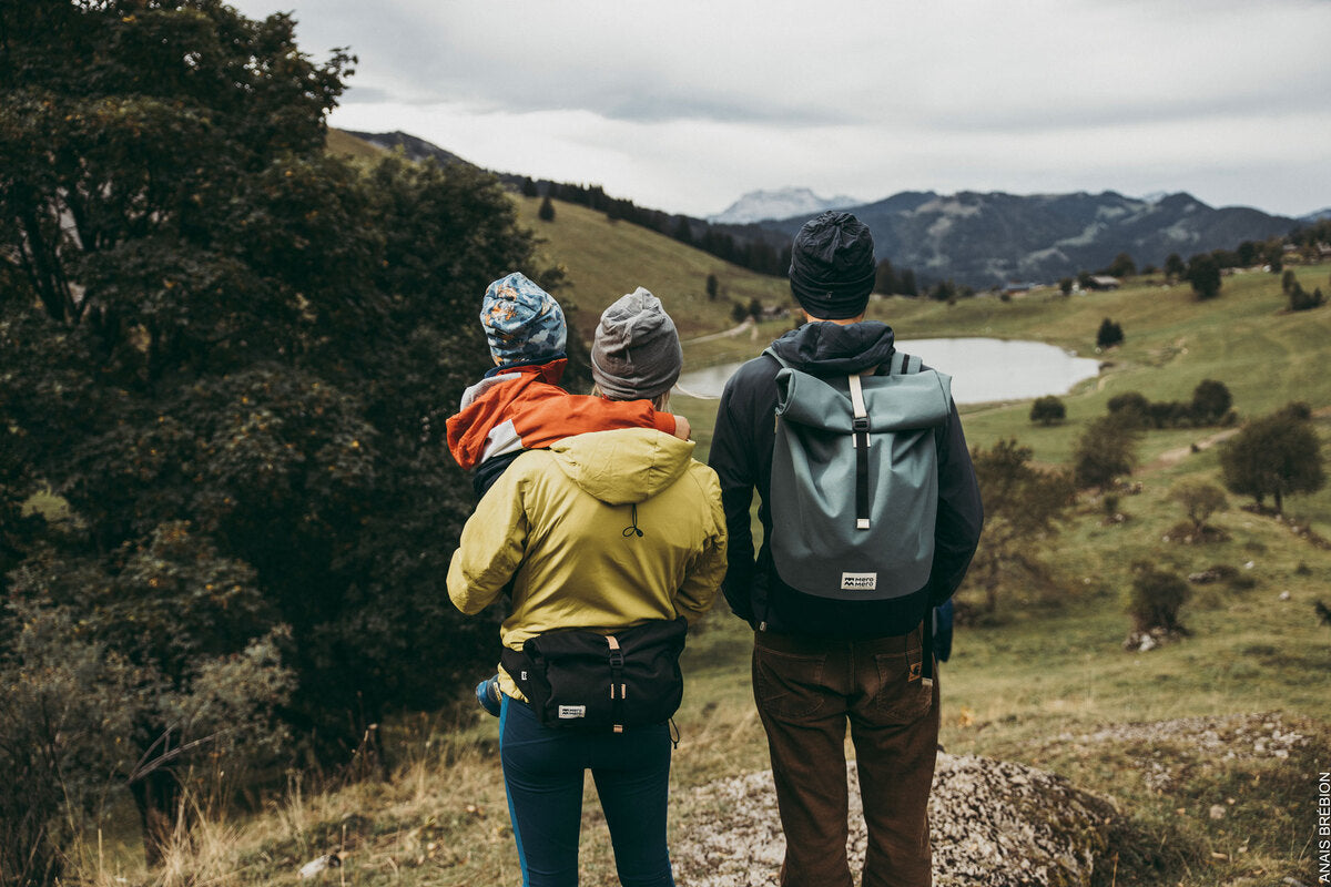 family during a hike, the dad wearing a light grey roll top backpack made of recycled materials