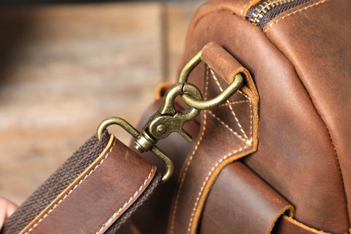 close up view of a adjustable removable shoulder strap on a leather travel duffle bag