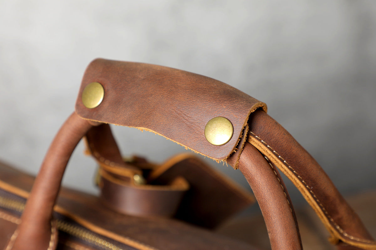 close up view of a comfortable and handy top handle on a leather travel duffle bag