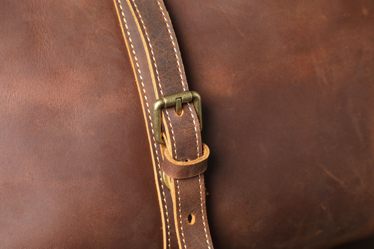 close up view of doubled top leather straps on a leather travel duffle bag