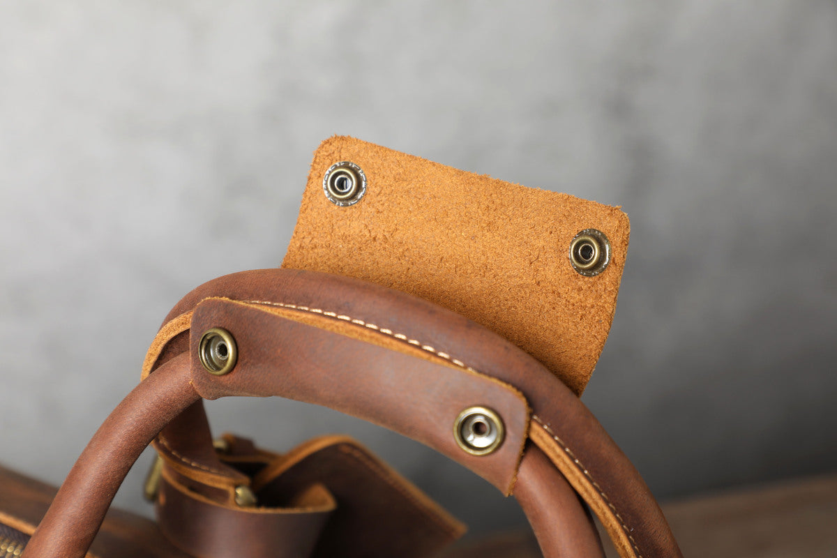 close up view of reinforced top leather handles on a leather travel duffle bag