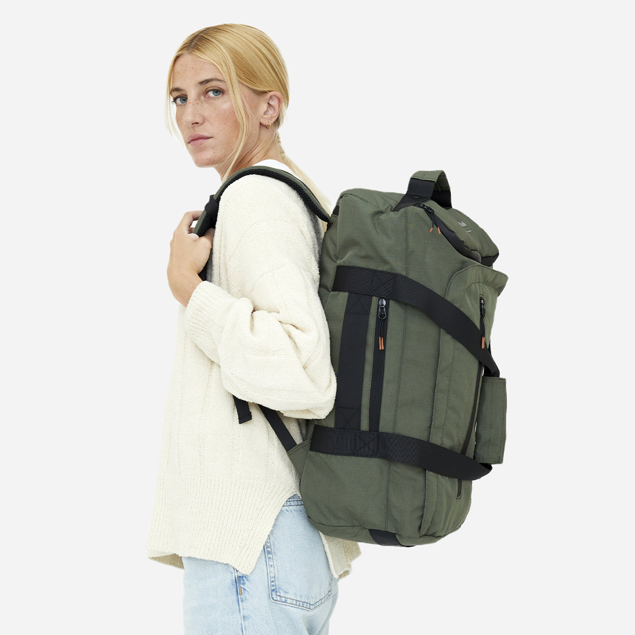 Femme portant un sac à dos convertible vert parfait pour les voyageurs éco-responsables, vue latérale