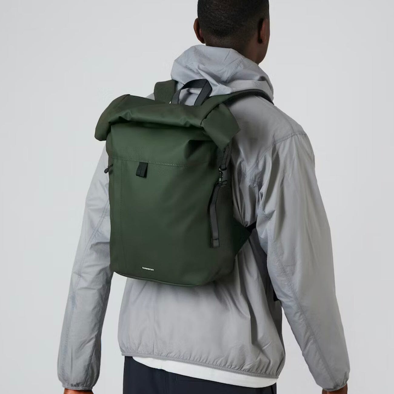 man model wearing small waterproof packable backpack recycled polyester roll top konrad sandqvist green