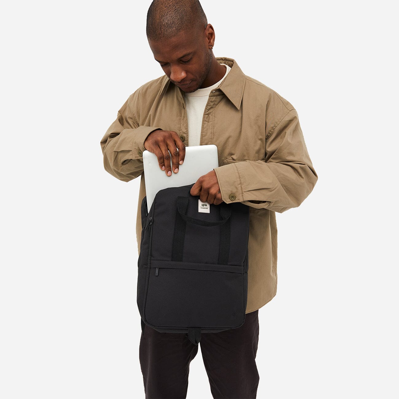 Man from the back storing his laptop in the eco-friendly black backpack