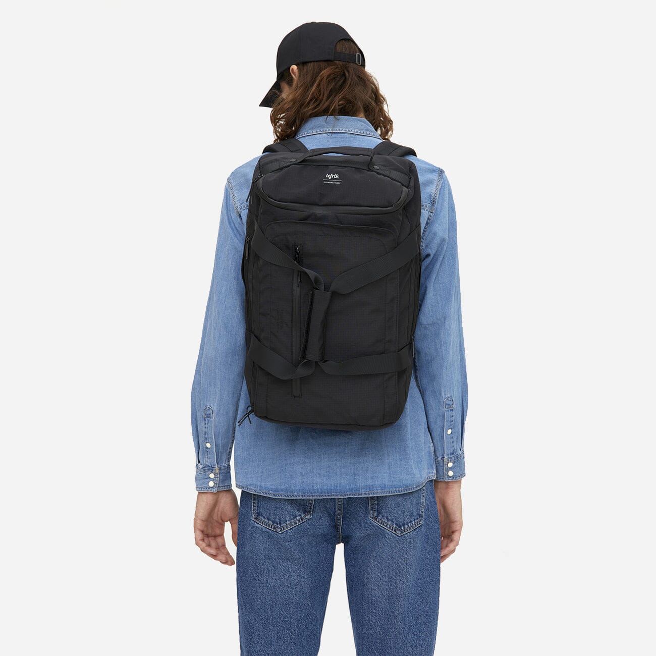 Man wearing black convertible backpack made from recycled materials, back view