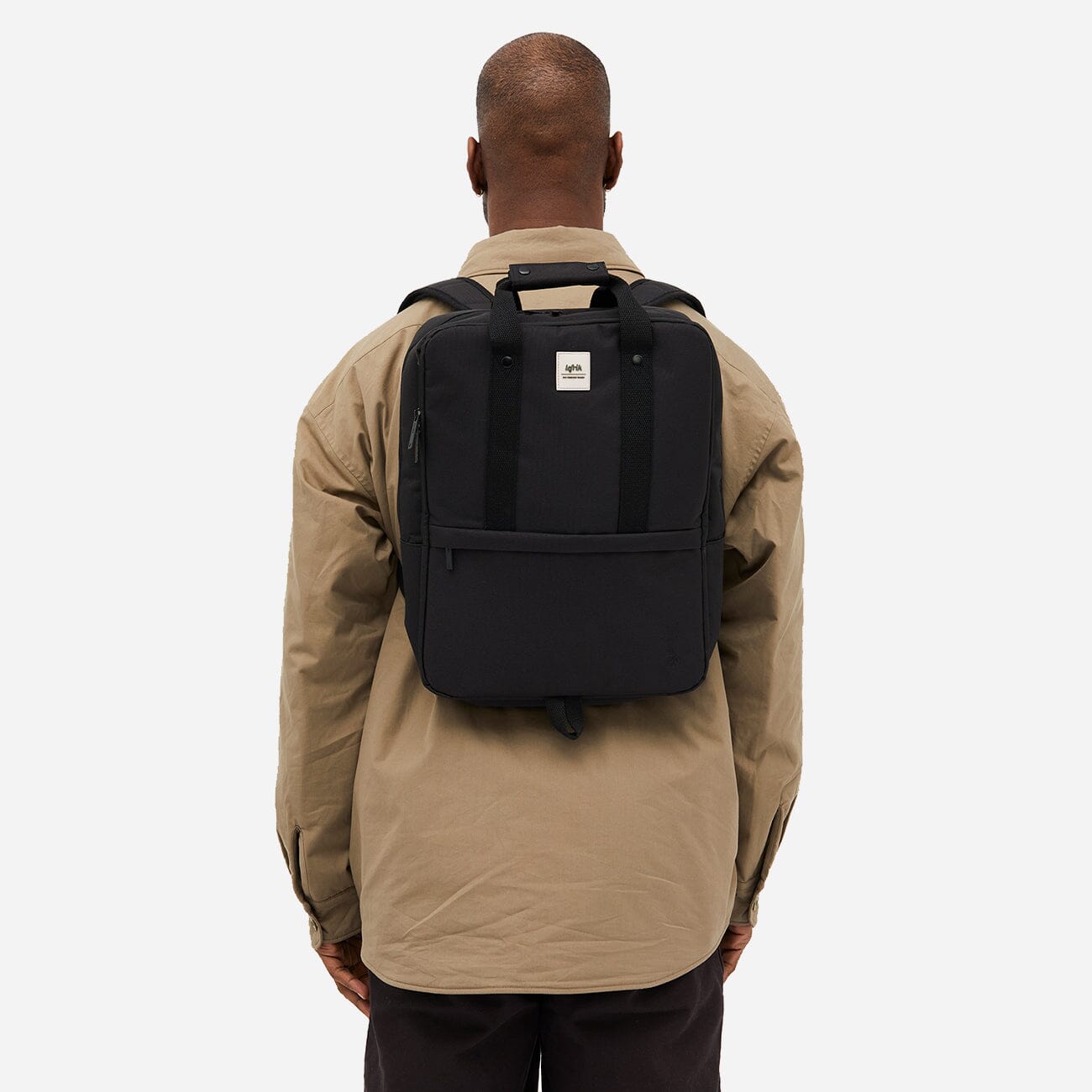 Man seen from the back carrying a sleek black backpack