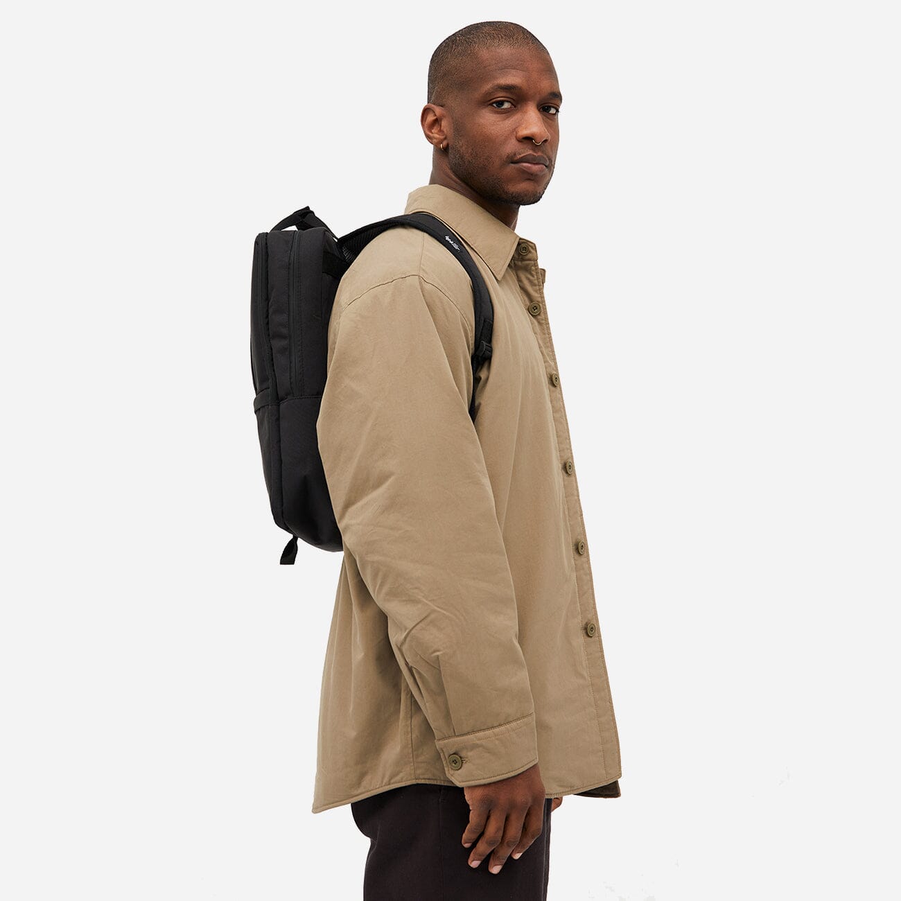 Side view of man carrying a sustainable blue and white backpack