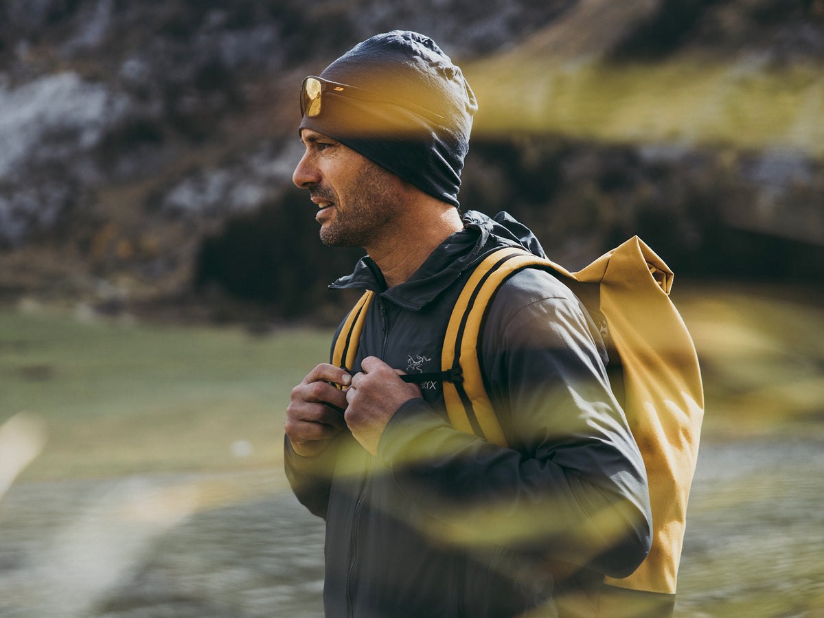 male hiker wearing a chai tai color recycled plastic backpack from the brand mero mero